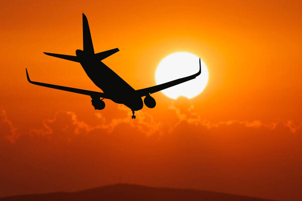 Silhouette of a passenger flight story with tourists landing at the airport. Airplane landing at sunset. passenger plane is landing in the airport runway at early morning at sunrise time