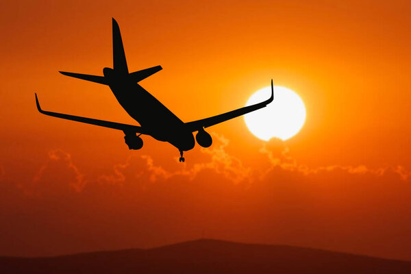 Silhouette of a passenger flight story with tourists landing at the airport. Airplane landing at sunset. passenger plane is landing in the airport runway at early morning at sunrise time