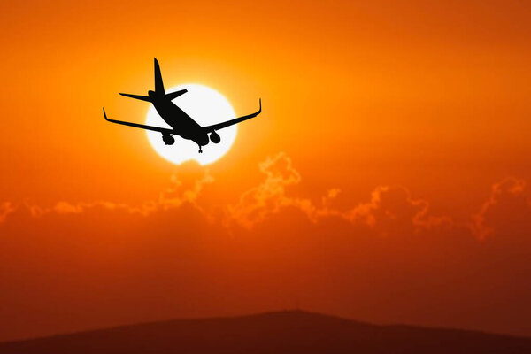 Silhouette of a passenger flight story with tourists landing at the airport. Airplane landing at sunset. passenger plane is landing in the airport runway at early morning at sunrise time