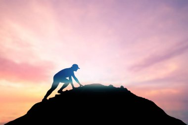 Adam güzel bir ışık çabasıyla dağın tepesine tırmanıyordu. Dağın yamacına tırmanan bir adamın silueti. Dağın zirvesine tırmanmaya kararlı genç adam. İnsanlar asla pes etmez, güç ve güç..