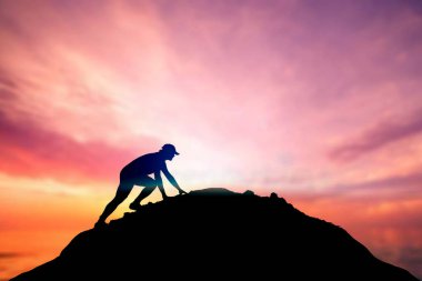 Adam güzel bir ışık çabasıyla dağın tepesine tırmanıyordu. Dağın yamacına tırmanan bir adamın silueti. Dağın zirvesine tırmanmaya kararlı genç adam. İnsanlar asla pes etmez, güç ve güç..