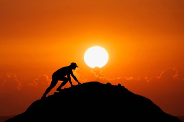 Adam güzel bir ışık çabasıyla dağın tepesine tırmanıyordu. Dağın yamacına tırmanan bir adamın silueti. Dağın zirvesine tırmanmaya kararlı genç adam. İnsanlar asla pes etmez, güç ve güç..