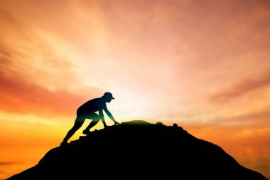 Adam güzel bir ışık çabasıyla dağın tepesine tırmanıyordu. Dağın yamacına tırmanan bir adamın silueti. Dağın zirvesine tırmanmaya kararlı genç adam. İnsanlar asla pes etmez, güç ve güç..