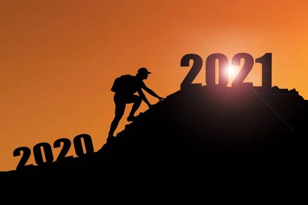 2021年の陽気なクリスマスと幸せな新年 2020年の崖から2021年の崖に雲の空と太陽の光でSilhouette男を歓迎します 山の上に2021年のバナーを持っている男 ハッピーニューイヤー2021のコンセプト — ストック写真