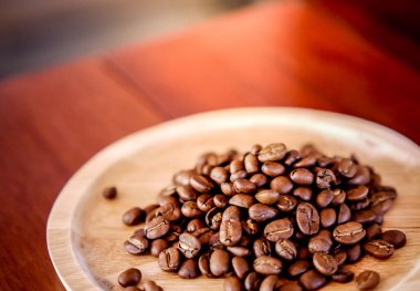 Orta pişmiş kahve çekirdekleri en üstteki ahşap tabakta kahverengi bir ahşap masaya yerleştirilir. Kahve ile ilgili çalışma geçmişi için resim fikri.