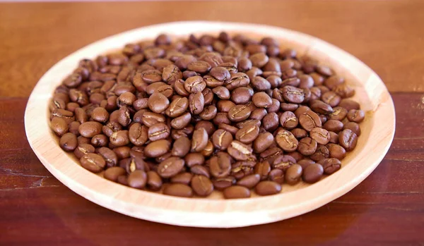 medium roast coffee beans In the top wooden dish is placed on a brown wooden table. Image idea for coffee related work background.