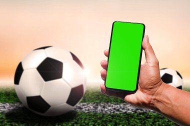 Futbol geçmişi olan bir adamın elinde yeşil boş ekran cep telefonu.