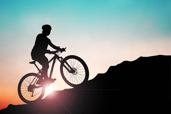 산악자전거 실루엣은 산에서 저녁에 아름다운 색깔로 훈련을 받습니다 산악자전거를 오르는 — 스톡 사진