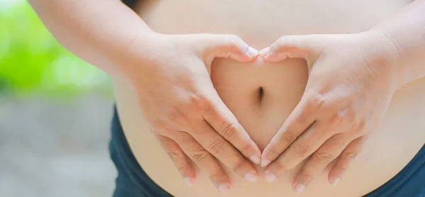 a pregnant woman with a heart-shaped hand placed on her stomach