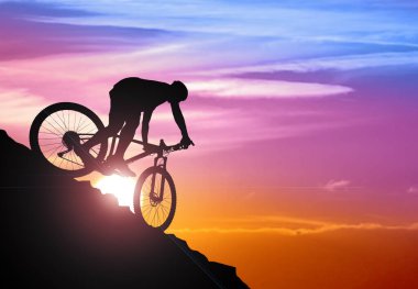 Akşamları dağdan inen bir bisikletçinin silüeti. Bisikletçi Kayadan Aşağı Bisiklete Biniyor. Gün doğumunda Güzel Dağlar 'da. Extreme Spor ve Dayanıklı Bisiklet Konsepti