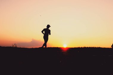 Akşamları koşuya hazırlanan bir adamın silüeti. Eğitim ve çalışma kavramları