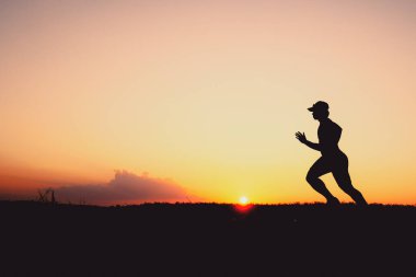 Akşamları koşuya hazırlanan bir adamın silüeti. Eğitim ve çalışma kavramları