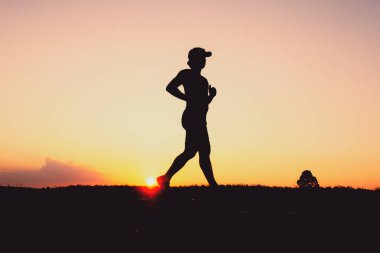 Akşamları koşuya hazırlanan bir adamın silüeti. Eğitim ve çalışma kavramları