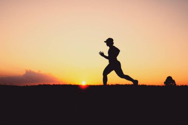 Akşamları koşuya hazırlanan bir adamın silüeti. Eğitim ve çalışma kavramları