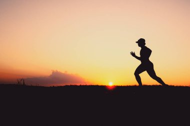 Akşamları koşuya hazırlanan bir adamın silüeti. Eğitim ve çalışma kavramları