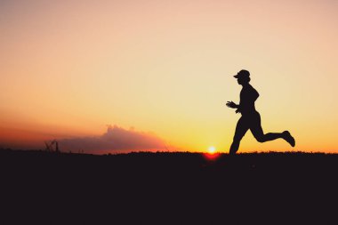 Akşamları koşuya hazırlanan bir adamın silüeti. Eğitim ve çalışma kavramları