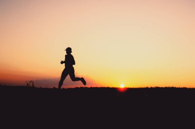 Akşamları koşuya hazırlanan bir adamın silüeti. Eğitim ve çalışma kavramları