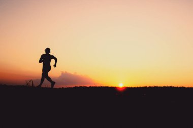 Akşamları koşuya hazırlanan bir adamın silüeti. Eğitim ve çalışma kavramları