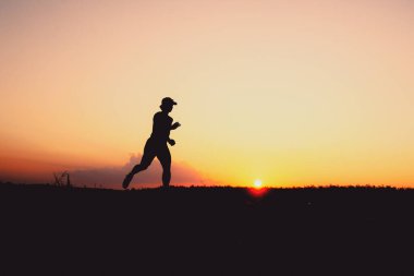Akşamları koşuya hazırlanan bir adamın silüeti. Eğitim ve çalışma kavramları