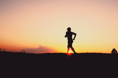 Akşamları koşuya hazırlanan bir adamın silüeti. Eğitim ve çalışma kavramları