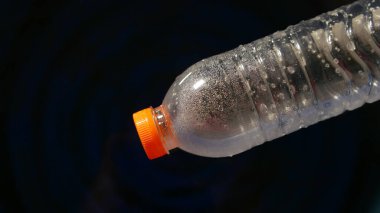 Siyah zemin üzerinde yüzen plastik su şişesi projelerde kolayca kullanılabilir. Suya saçılmış plastik atık. Atık ve plastik kirliliği kavramı