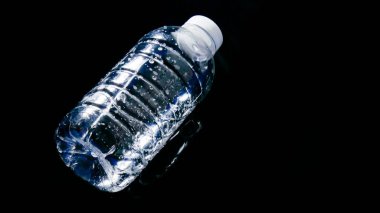 Siyah zemin üzerinde yüzen plastik su şişesi projelerde kolayca kullanılabilir. Suya saçılmış plastik atık. Atık ve plastik kirliliği kavramı