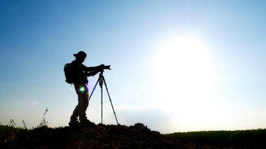Bir jest silueti profesyonel manzara seyahat fotoğrafçısı dağda fotoğraf çekiyor..