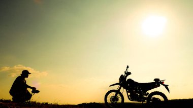 Profesyonel manzara fotoğrafçılarının siluetleri. Akşamları bir motokrosla