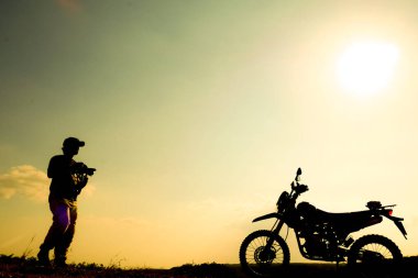 Profesyonel manzara fotoğrafçılarının siluetleri. Akşamları bir motokrosla