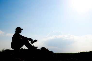 Profesyonel bir manzara fotoğrafçısının silueti dağda bir kamera tutuyor..