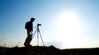 Bir jest silueti profesyonel manzara seyahat fotoğrafçısı dağda fotoğraf çekiyor..