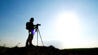 Bir jest silueti profesyonel manzara seyahat fotoğrafçısı dağda fotoğraf çekiyor..