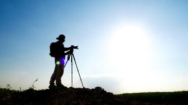 Bir jest silueti profesyonel manzara seyahat fotoğrafçısı dağda fotoğraf çekiyor..