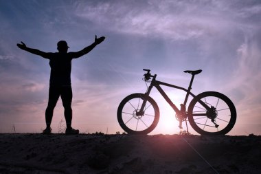 Akşamları bisikletle egzersiz yapan bir adam ellerini kaldırıyor..