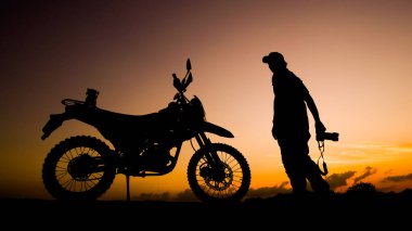 Siluet fotoğrafçısı akşamları motosikletli off-road ya da motokroslu maceralar. seyahat ve macera kavramı