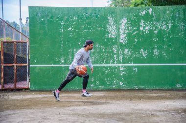 26 Haziran 2021 'de COVID-19 krizi sırasında dışarıda basketbol oynayarak egzersiz yapan adam, Surat Thani, Tayland.