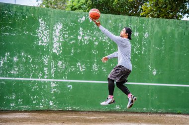 26 Haziran 2021 'de COVID-19 krizi sırasında dışarıda basketbol oynayarak egzersiz yapan adam, Surat Thani, Tayland.