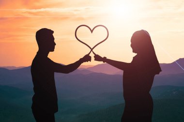 Erkek ve kadın çiftlerin siluetleri işaret parmaklarıyla birbirlerine dokunuyorlar. Aşk sonsuza dek konsept