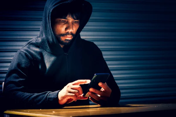 Mysterious man in hoodie on dark background. Dangerous criminal. Silhouette of man in the hood, dark mysterious man hoodie, murderer, hacker, anonymus on the black background with free space