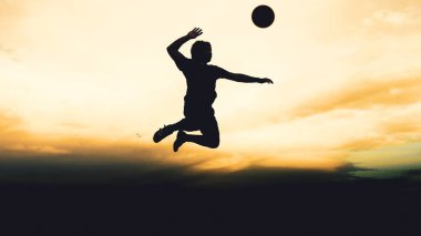 Bir voleybol oyuncusunun silueti dağda pratik yapıyor ve akşam çok güzel bir manzara sunuyor.