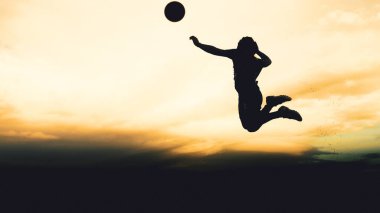 Bir voleybol oyuncusunun silueti dağda pratik yapıyor ve akşam çok güzel bir manzara sunuyor.