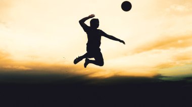 Bir voleybol oyuncusunun silueti dağda pratik yapıyor ve akşam çok güzel bir manzara sunuyor.