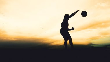 Bir voleybol oyuncusunun silueti dağda pratik yapıyor ve akşam çok güzel bir manzara sunuyor.