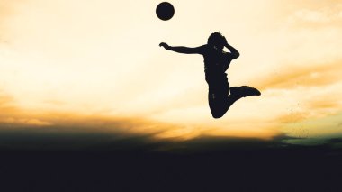 Bir voleybol oyuncusunun silueti dağda pratik yapıyor ve akşam çok güzel bir manzara sunuyor.
