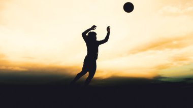 Bir voleybol oyuncusunun silueti dağda pratik yapıyor ve akşam çok güzel bir manzara sunuyor.