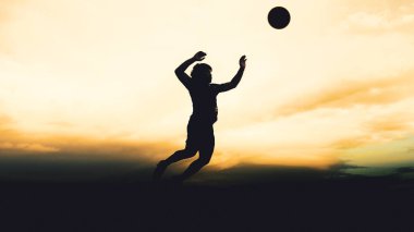 Bir voleybol oyuncusunun silueti dağda pratik yapıyor ve akşam çok güzel bir manzara sunuyor.