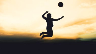 Bir voleybol oyuncusunun silueti dağda pratik yapıyor ve akşam çok güzel bir manzara sunuyor.