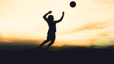 Bir voleybol oyuncusunun silueti dağda pratik yapıyor ve akşam çok güzel bir manzara sunuyor.