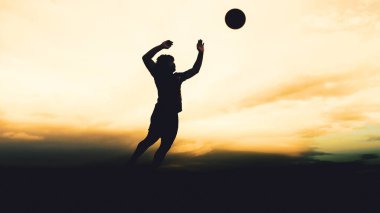 Bir voleybol oyuncusunun silueti dağda pratik yapıyor ve akşam çok güzel bir manzara sunuyor.