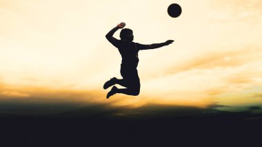 Bir voleybol oyuncusunun silueti dağda pratik yapıyor ve akşam çok güzel bir manzara sunuyor.